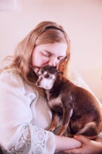 a woman hugs her chihuahua dog