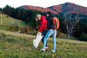 Happy mature woman enjoys hiking and adventure with her daughter and their cute dog in the sunset of a beautiful autumn day