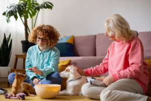 Caucasian ginger girl playing playstation with her grandmother at home with their pets enjoying time together