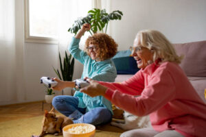 Grandmother and granddaughter with dogs playing playstation in the living room