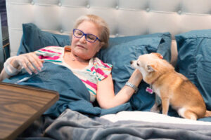 A caucasian woman is at home recuperating from an illness. She is lying in bed with her pet Chihuahua. Shot with a Canon 5D Mark lll.