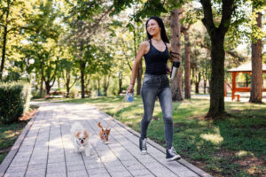 oung woman jogging in the park with her two small dogs